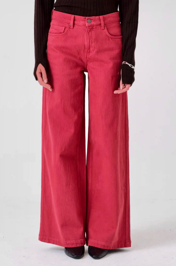 Close up of a person wearing faded rose pink wide-leg jeans with pockets, fly zip and button.