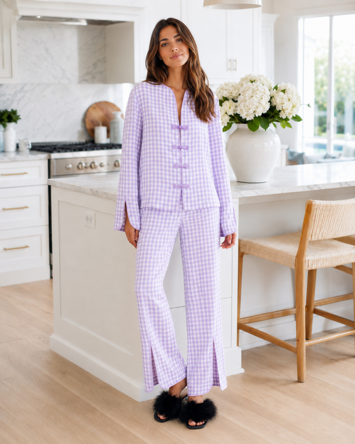 Woman in purple checkered pajamas standing in a kitchen.