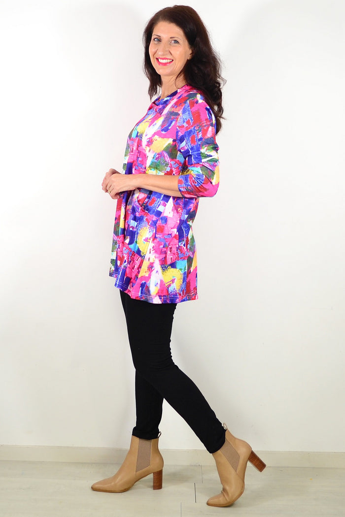Wishstone Splash of Colour Tunic Top featuring vibrant patterns, long sleeves, and a relaxed fit, displayed on a hanger.