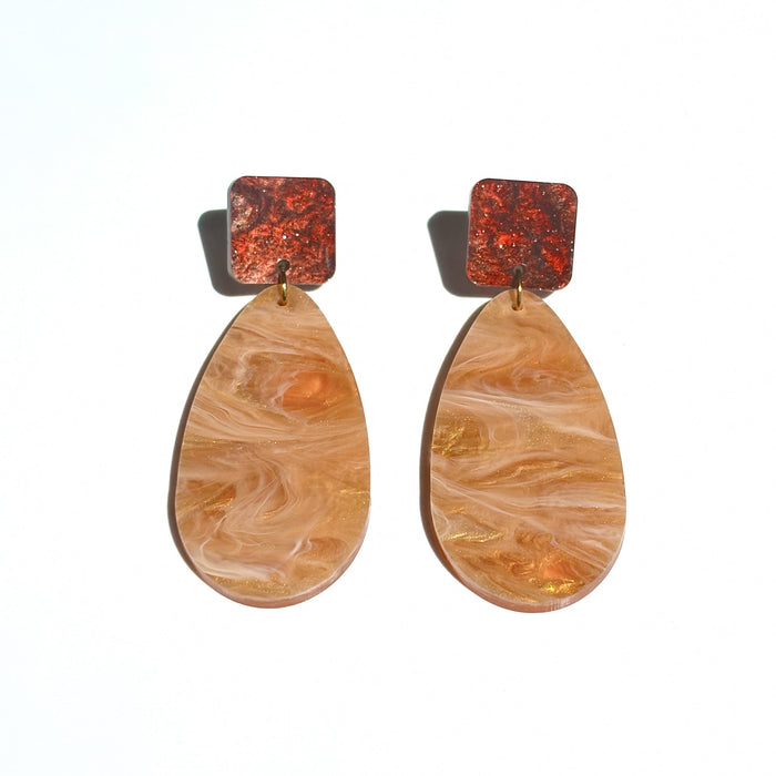 Light brown colour acrylic dangle earrings in a large tear drop shape attached to a square shape in a reddish dark brown sparkly colour at the top.
