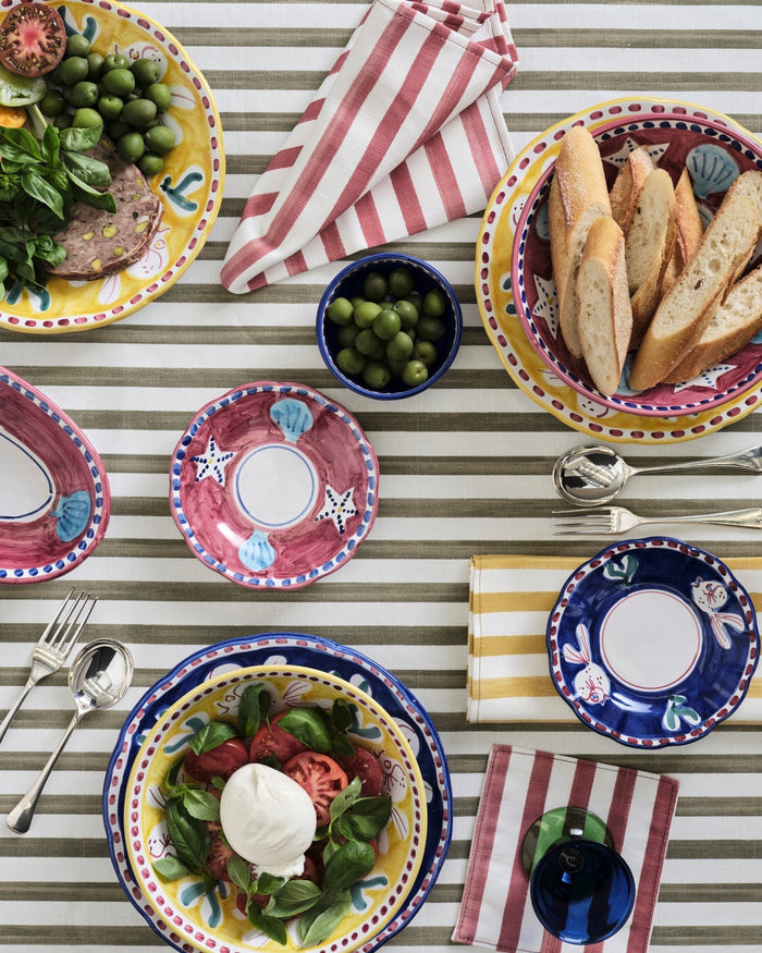 Various coloured striped Napkins on an olive striped tablecloth iin a table setting - ANNIE.G