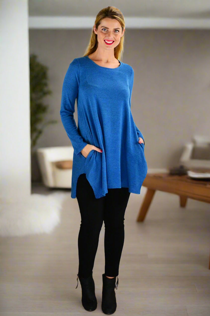 Teal blue knit tunic top by Hourglass, featuring a loose fit and long sleeves, displayed on a model against a neutral background.