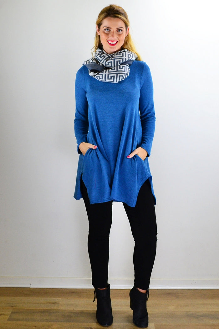 Hourglass teal blue knit tunic top with long sleeves and a relaxed fit, shown on a hanger.