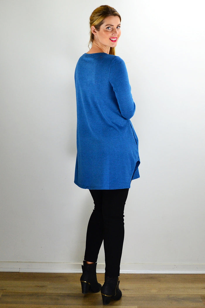 Teal blue knit tunic top from Hourglass, featuring a relaxed fit and textured fabric, displayed on a hanger.