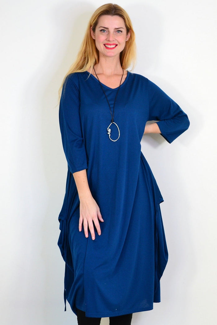 Lilia Whispers teal relaxed oversized tunic dress hanging on a wooden hanger, showcasing its flowing fabric and casual style.