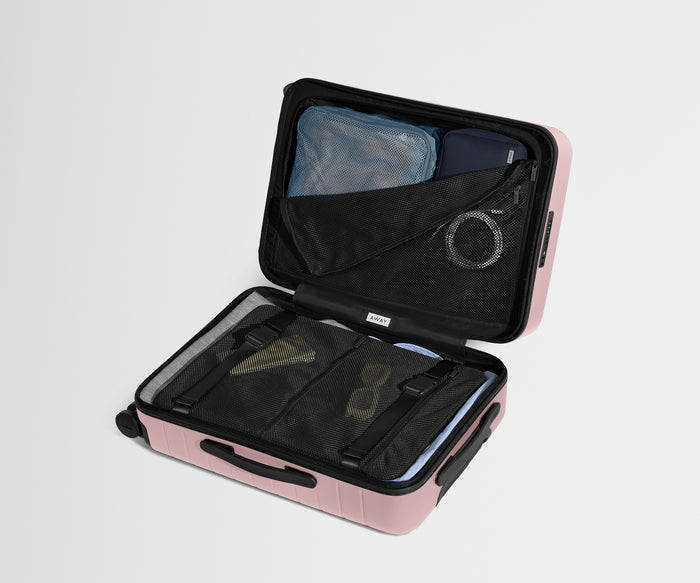 The Bigger Carry-On suitcase in Blush Pink shown open on its side and packed with Away's packing organizers to show capacity and the interior compression system, designed to help you pack more in
// 
Our signature interior compression system allows you to stay more organized. Paired with The Insider Packing Cubes.