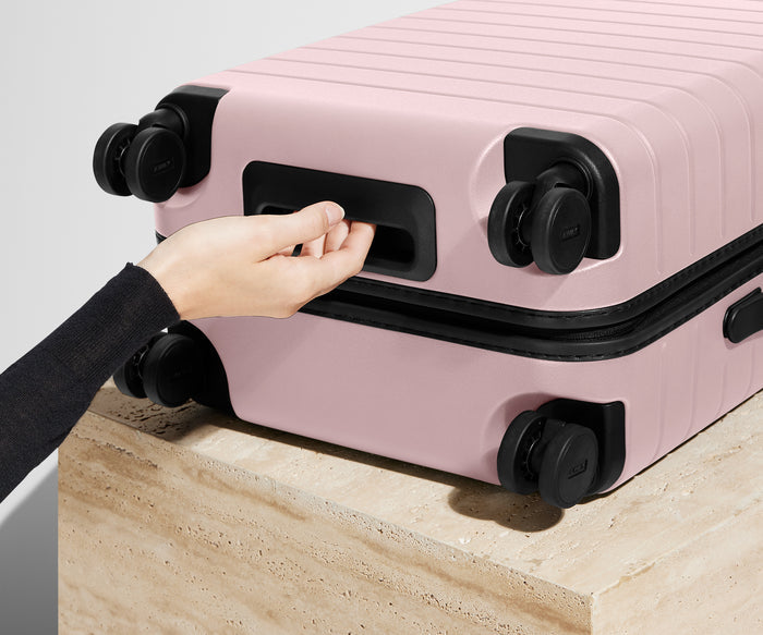 The Carry-On suitcase in Blush Pink shown from below highlighting the underside grab handle
// 
Underside grab handle that makes it easier to lift and carry your suitcase.