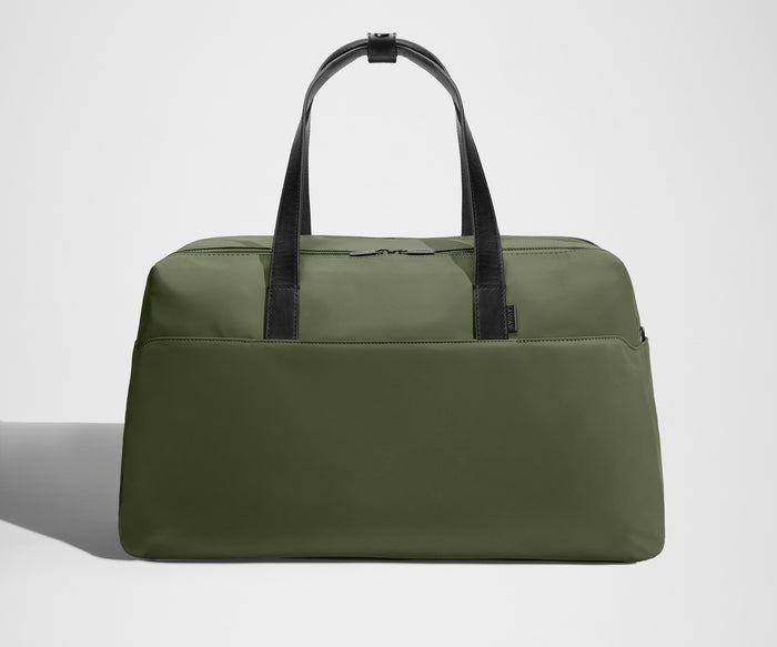 Green duffel bag with black straps on a light gray background