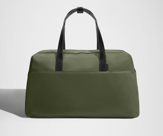 Green duffel bag with black straps on a light gray background