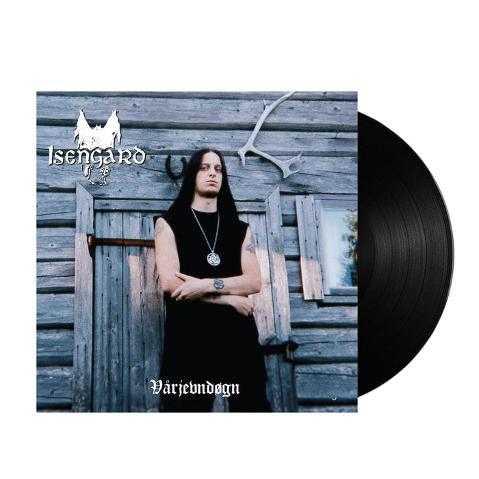 A vinyl record partially visible beside an album cover shows Fenriz with long black hair and a pendant, arms crossed before a rustic wooden building. The cover reads “Isengard” and “Vårjevndøgn”—a vintage metal classic from Isengard.