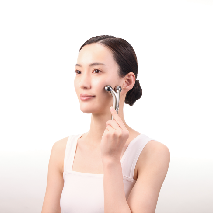 Woman using a skincare device on her face against a white background
