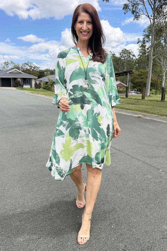 White and green paint splash tunic dress by Ruby Rain, featuring a flowing silhouette and artistic design, displayed on a hanger.