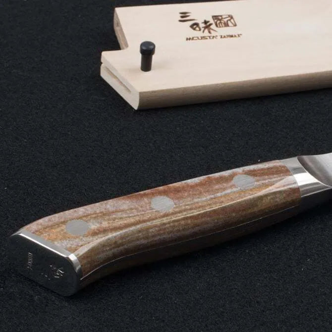 A Zanmai Pro Gyuto SE knife with a distinctive handle pattern and a natural wood saya cover.