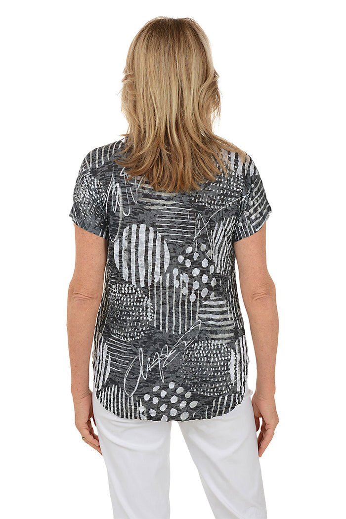 Woman wearing a black and white patterned top with white pants on a white background
